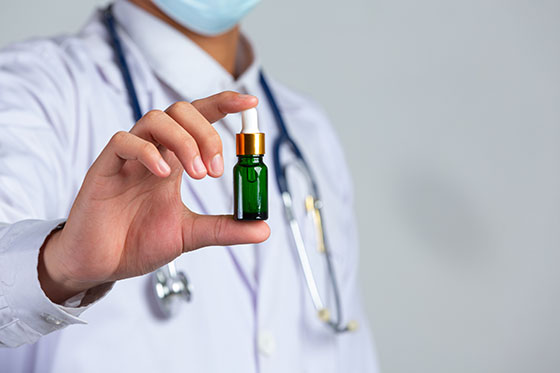 Medical professional holding a bottle of drops, possibly cannabis CBD extract.