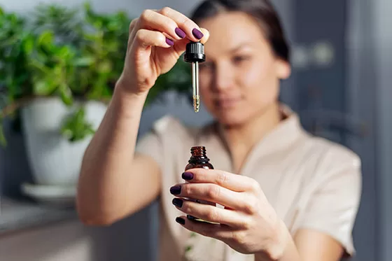 Lady possibly medical worker using CBD oil from a dropper and liquid bottle.