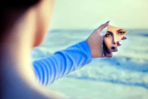 Woman looking at herself in a piece of mirror