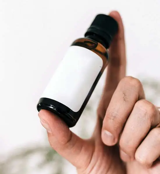 Hand holding a bottle that looks like it may contain drops or concentrate of some sort.