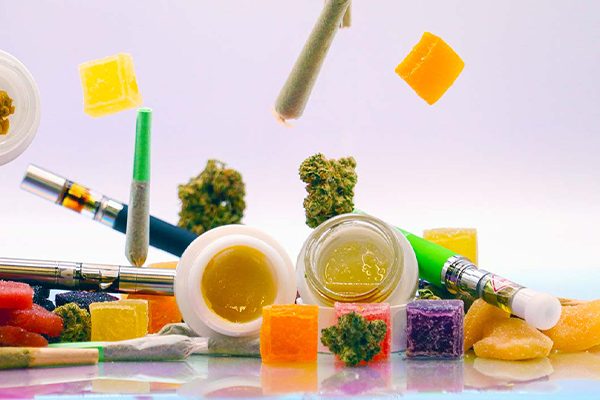 Variety of cannabis products on a white background, including edibles, blunts, flower, topicals and vape cartridges.
