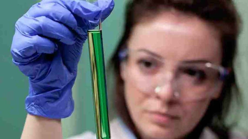 Medical professional holding up a test tube with green liquid