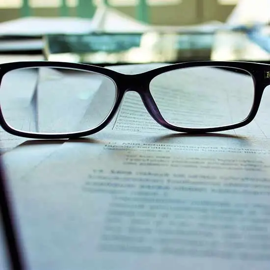 Closeup of a pair of glasses on a printed paper out of focus, representation of legalities and laws.