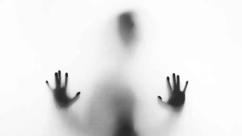 Outline of a persons hands pressed against frosted glass