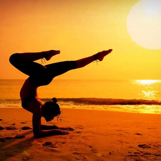 Woman doing a difficult yoga exercise pose on a beach