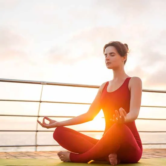 Healthy looking woman meditating in a yoga pose in the outdoors.