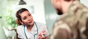 Young medical professional attentively speaking with a soldier in uniform. Soldiers, who often suffer from PTSD, can resort to medical cannabis under the supervision of a doctor.