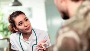 Young medical professional attentively speaking with a soldier in uniform. Soldiers, who often suffer from PTSD, can resort to medical cannabis under the supervision of a doctor.