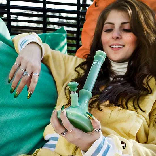 Young woman lying back holding a bong