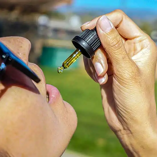 Woman consuming CBD from a dropper.