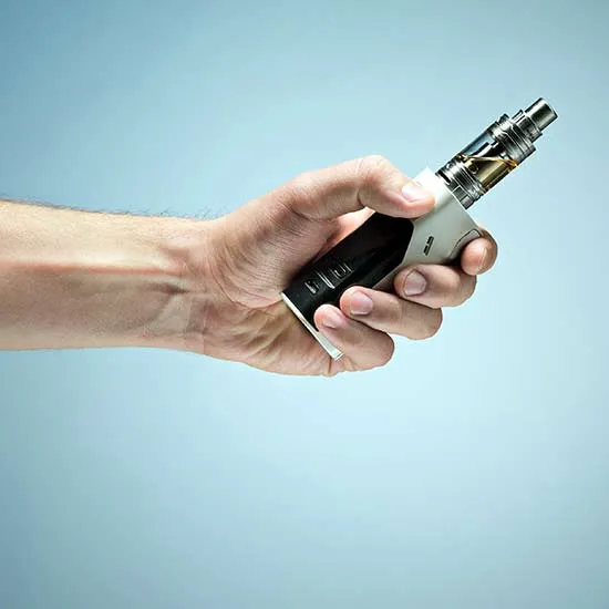 Hand holding a vaporizer with cartridge.