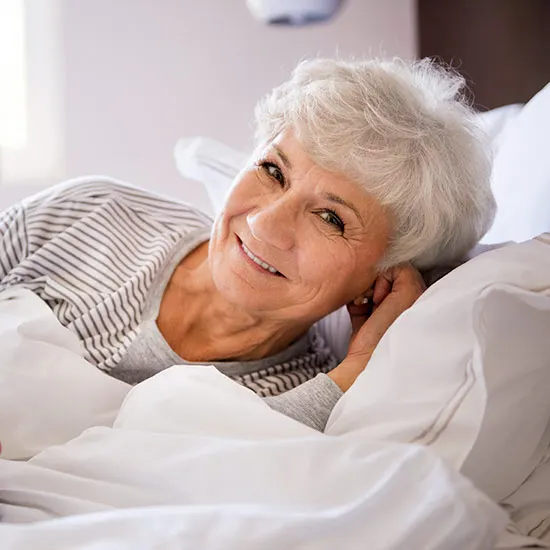 Cannabis can help improve sleep quality. A smiling elderly lady in bed.