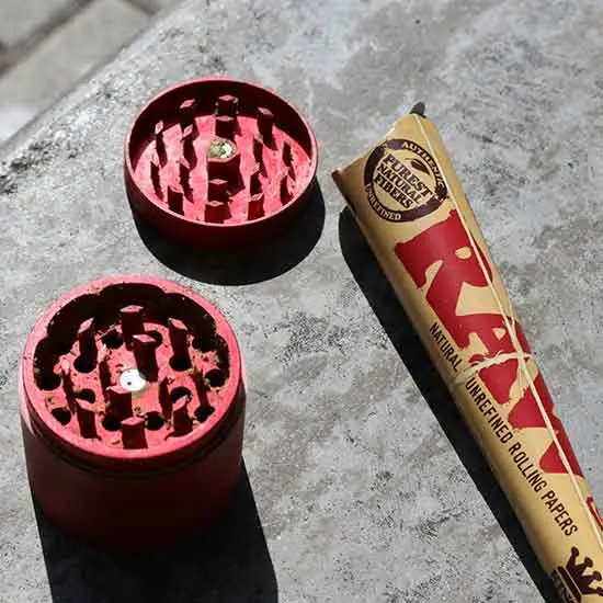 A cannabis grinder and rolling paper.