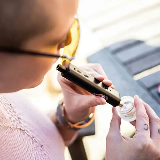 Person using a concentrate. Oil Day celebrates cannabis oil in all its forms.