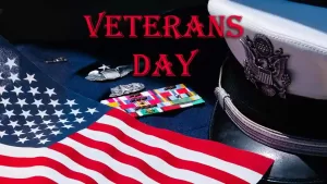 US flag, medals and a uniform cap with the words VETERANS DAY