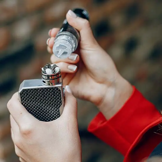 Hands using a cannabis vaporizer